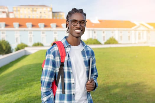 African American Student Guy With Backpack And Laptop Stands Outside