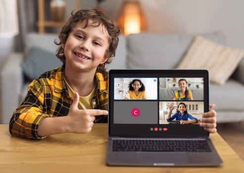 Cute boy schooler showing laptop with online lesson screen