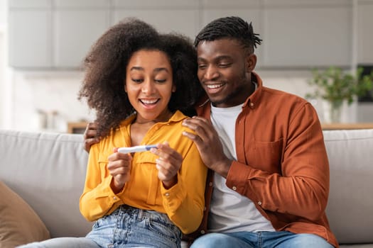 Joyful Married African American Couple Holding Positive Pregnancy Test Indoors