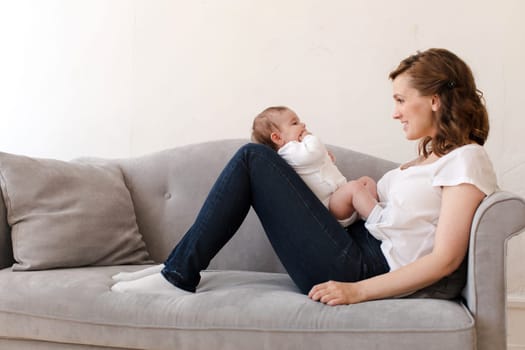 Happy mother with baby sitting on sofa