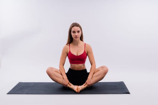 Beautiful woman doing Lotus of Padmasana or Kamalasana pose on a yoga class. Studio shot.