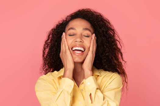 Ecstatic black woman laughing with hands on cheeks