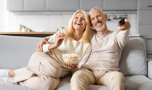 Joyful old man and woman couple watching TV at home