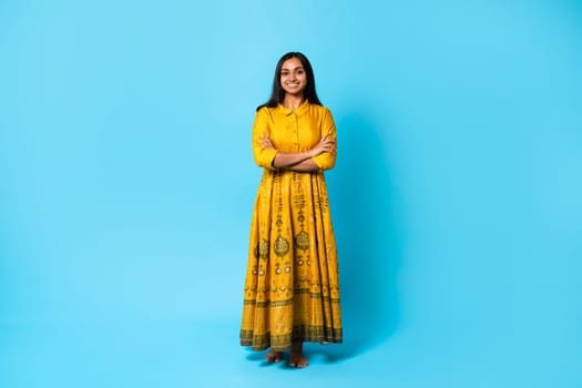 Smiling hindu lady wearing dress posing with folded arms, studio