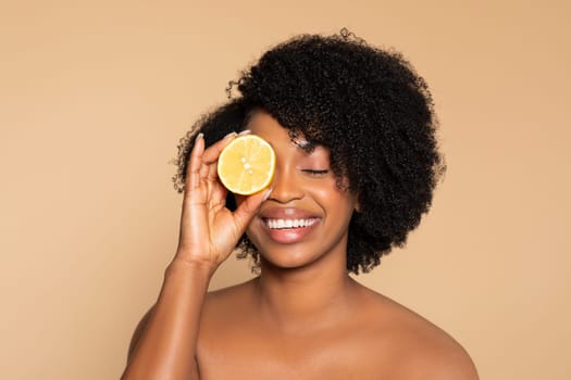 Joyful black woman with lemon, natural beauty theme