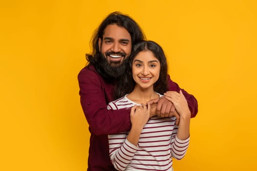Portrait of loving young hindu couple posing on yellow background