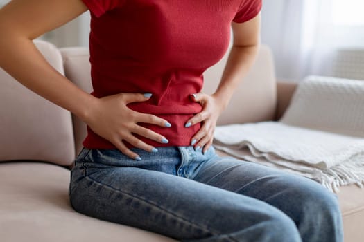 Unrecognizable woman experiencing abdominal pain at home