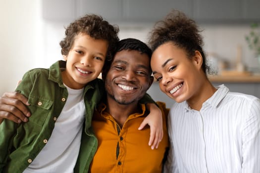 Black family with smiling parents and child boy in close hug
