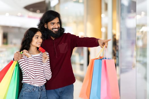 Excited eastern couple shopping together at mall