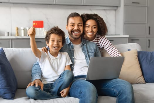 Cheerful Black Family Using Laptop Together At Home And Showing Credit Card