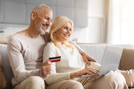 Happy senior man and woman with laptop and credit card