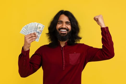 Emotional handsome millennial indian man holding bunch of cash