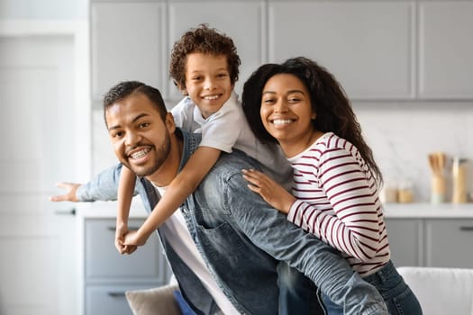 Cheerful Black Family With Little Son Hugging And Smiling At Camera