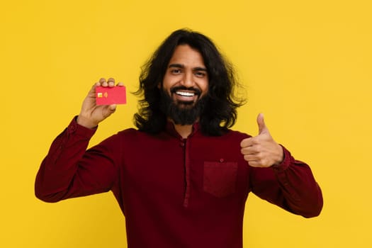 Happy hairy hindu man showing credit card and thumb up