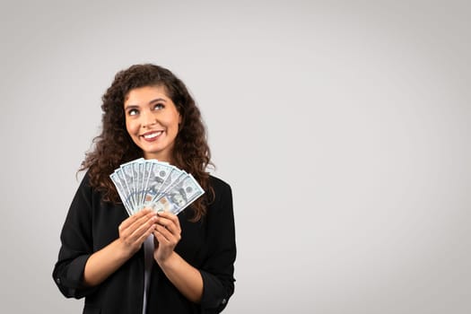 Businesswoman holding money with joyful look, free space