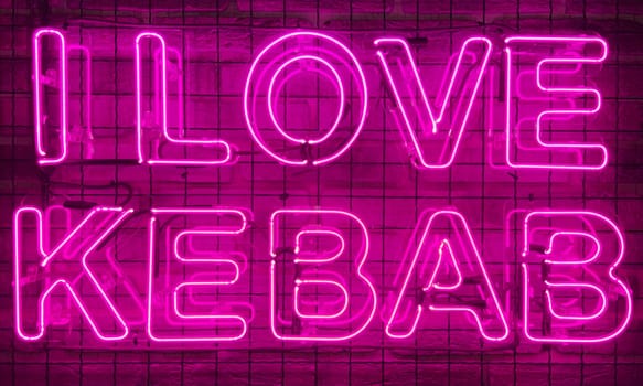 Neon shining sign in pink or purple color on a brick wall with the inscription or slogan I love kebab. Brick wall, background. Bright electric neon light. Cafe-restaurant Doner Kebab.