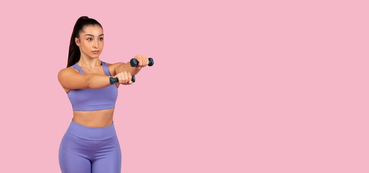 Focused woman exercising with dumbbells on pink, panorama