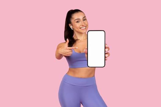 Cheerful woman showing smartphone screen, wearing gym clothes