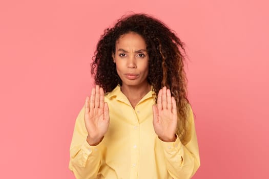 Black woman with stop gesture in yellow shirt