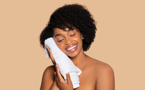 Happy black woman with curly hair holding white towel