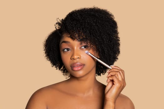 Woman applying eye makeup with brush, neutral tone
