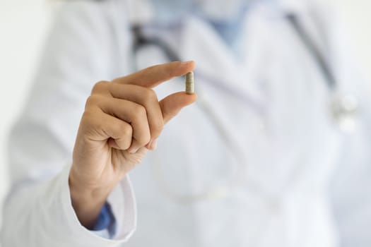 Unrecognizable caucasian woman doctor in white coat shows capsule pill