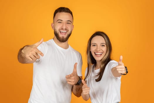 Two cheerful young adults, a bearded man and a smiling woman, give enthusiastic thumbs up