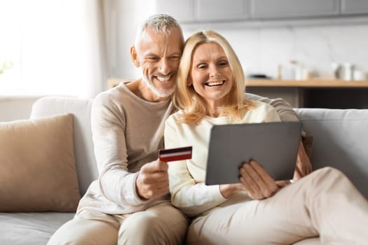 Happy senior man and woman with digital tablet, credit card