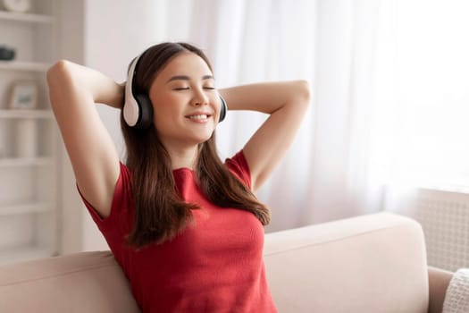 Beautiful Smiling Asian Woman In Wireless Headphones Listening Music At Home,