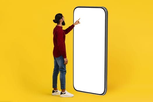 Cool young indian man using big phone with white screen