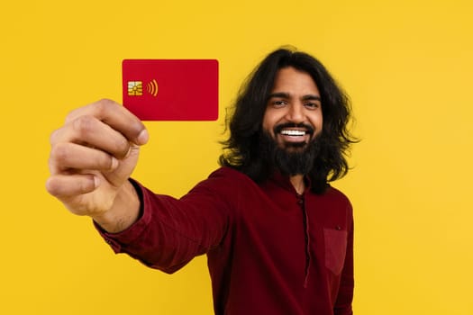 Cheerful young indian guy showing bank card