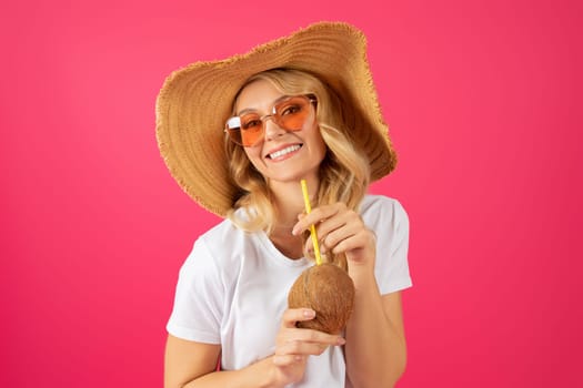 Portrait of cheerful blonde young lady holding coconut cocktail drink