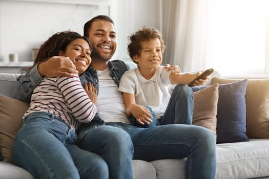 African american family of three cuddling and watching television together at home