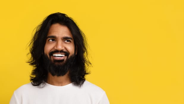 Positive millennial hindu guy looking at blank space