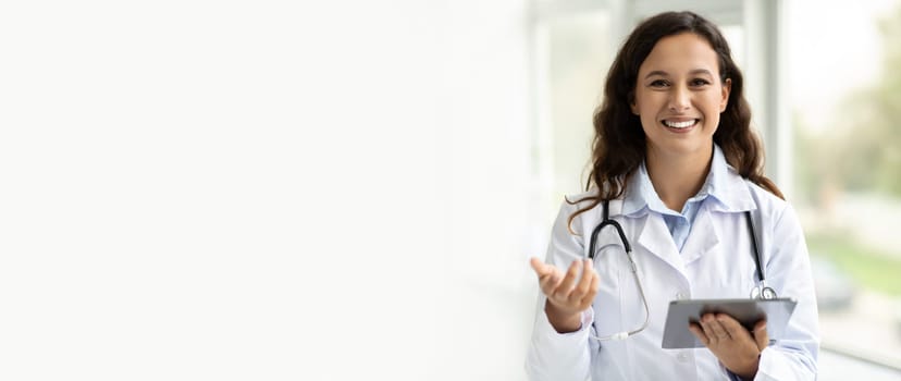 Smiling young woman doctor in white coat work on tablet