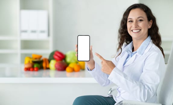 Happy european lady doctor nutritionist in white coat recommends app