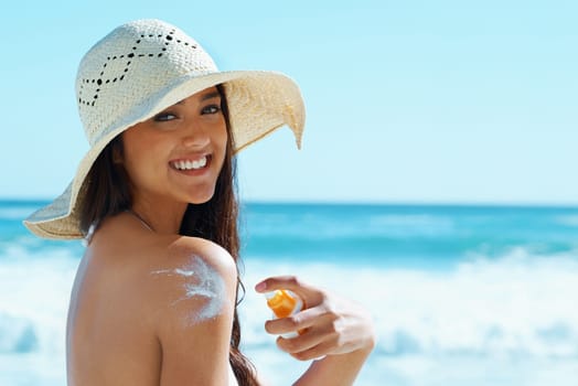 Woman, portrait and beach with sunscreen on shoulder for skin, health and happy by waves for vacation. Girl, person and smile with hat, serum and sunblock for uv light, sunburn and safety in Naples