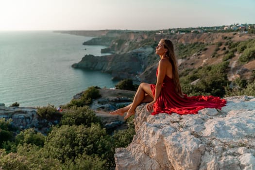 Woman sunset sea red dress, portrait happy beautiful sensual woman in a red long dress posing above the sea on sunset.