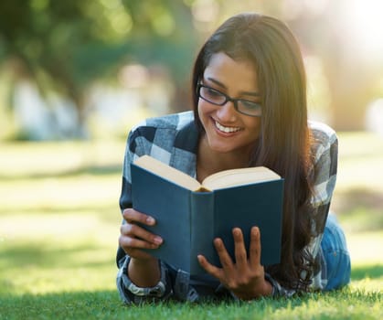 Happy woman, student and reading book on green grass for literature, studying or story in nature. Female person, smart or young adult with smile or glasses for chapter, learning or education at park