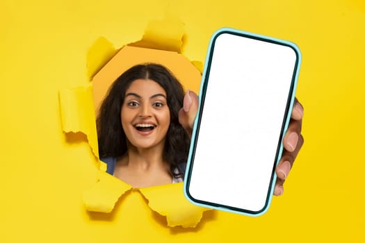 hindu lady holding phone in hand breaking through yellow backdrop