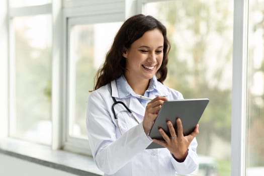 Smiling young woman doctor using digital tablet