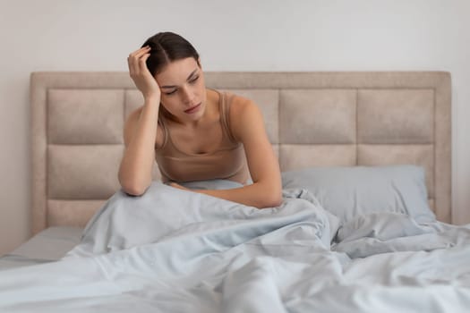 Concerned woman sitting in bed holding her head