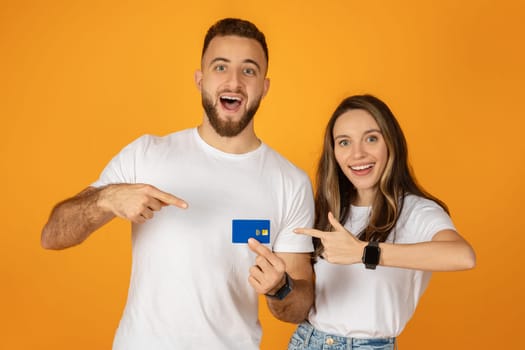 Enthusiastic young couple pointing at a credit card held by the woman