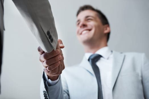 Low angle, businessman and shaking hands with partner, colleague and smile for deal or promotion. Man, consult and hand for contract agreement, interview and advice for agency and office partnership