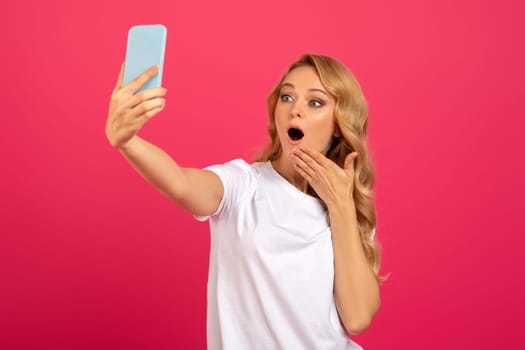 Amazed Blonde Lady Making Selfie On Phone Over Pink Background