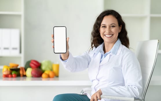Friendly young woman nutritionist showing phone with blank screen