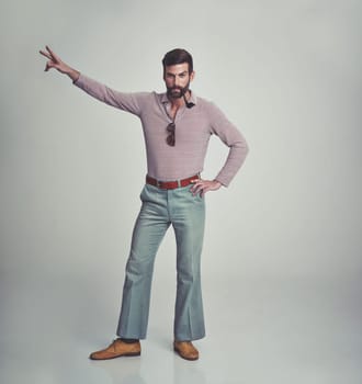 70s, fashion and portrait of man with retro or vintage aesthetic in gray background of studio. Smoking, pipe and person dance with peace and confidence in funky sunglasses and unique style from past