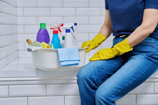 House cleaning concept, basin with cleaning products and hands in gloves