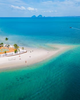 aerial view at Koh Muk a tropical island with palm trees and soft white sand, and a turqouse colored ocean in Koh Mook Trang Thailand, top view at a beautiful tropical island in Thailand