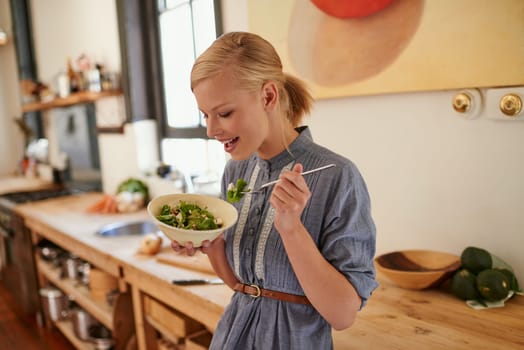 Woman, salad and eating in kitchen for health nutrition for wellbeing, ingredients or fibre. Female person, bowl and vegetable meal in apartment or diet leafy greens or lettuce food, recipe or Canada